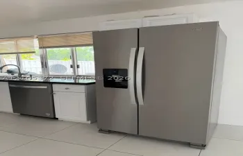 Stainless steel side-by-side refrigerator, stainless steel dishwasher, white cabinetry, dark stone countertop, and tile flooring