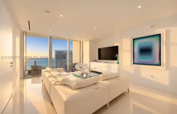 Expansive floor-to-ceiling windows, recessed lighting, sleek white tile flooring, and a built-in media console