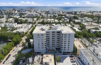 Multi-story residential building featuring a ground-level swimming pool, perimeter landscaping, and multiple private balconies