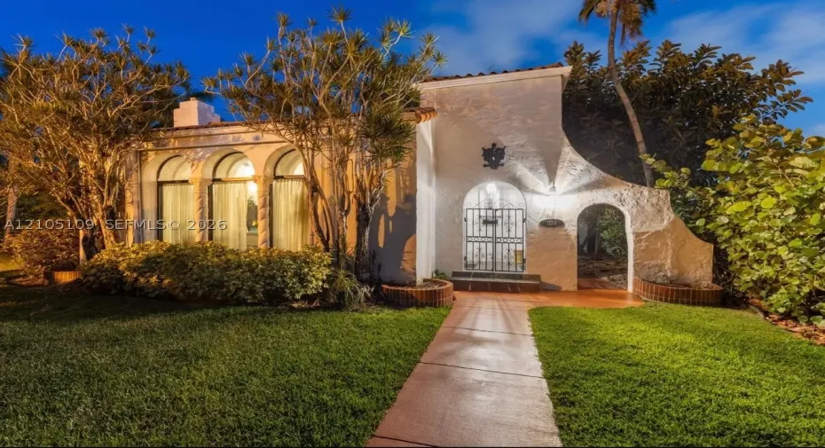 Stucco exterior with an arched entry, prominent arched windows, and an ornamental gate