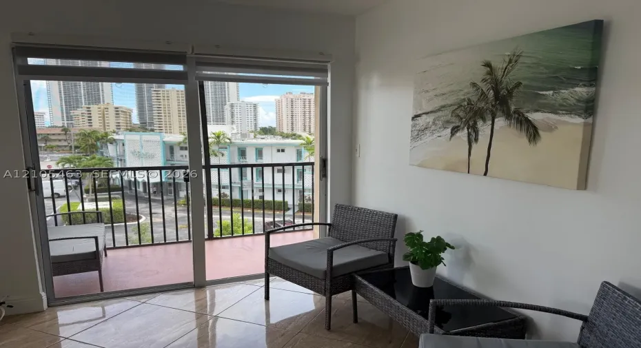 Sliding glass doors opening to a private balcony with a metal railing, overlooking city buildings