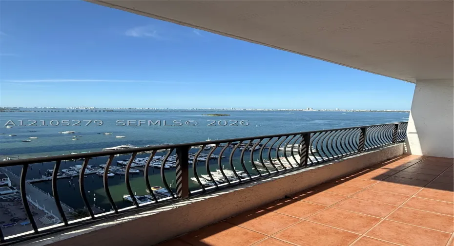 Balcony with terracotta tile flooring, metal railing, and expansive water views with a marina