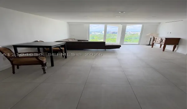 Large format tile flooring, recessed lighting, and floor-to-ceiling glass panel doors opening to an exterior balcony