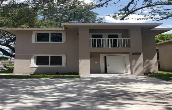 Two-story stucco exterior with a white entry door, upper-level balcony, and double-pane windows