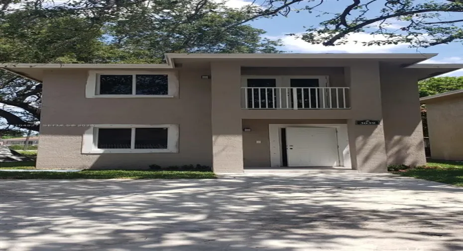 Two-story stucco exterior with a white entry door, upper-level balcony, and double-pane windows
