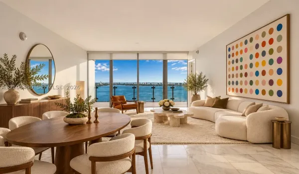 Floor-to-ceiling glass windows, stone flooring, balcony with glass railing, and water backdrop