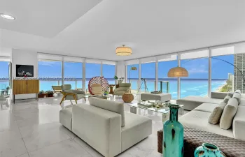 Elegant living area featuring Carrara marble flooring, floor-to-ceiling windows, stunning ocean views, and recessed ceiling lighting.