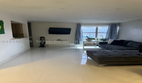 Recessed ceiling lighting, glossy tile flooring, a pass-through window with a stone-finish countertop, and a large window with light-toned drapery