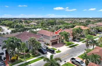 Two-story residence featuring a tile roof, paved driveway, attached garage, and mature palm landscaping