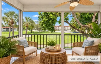 Screened porch featuring a ceiling fan, black railings, and a green landscape backdrop