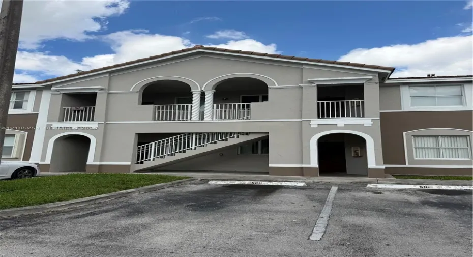 Stucco exterior with arched architectural details, tile roof, and white railings