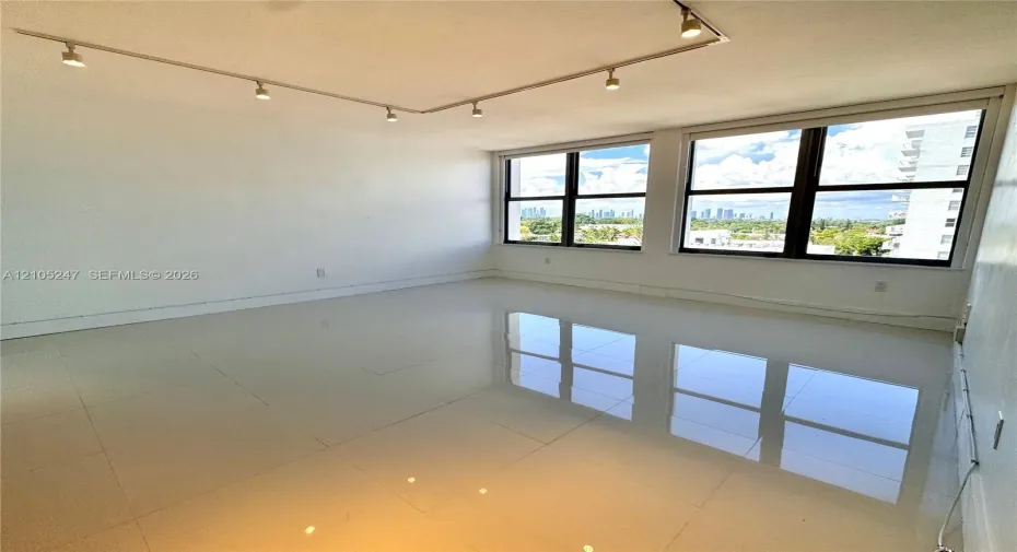 Track lighting fixtures, expansive windows, city horizon, and reflective tile flooring