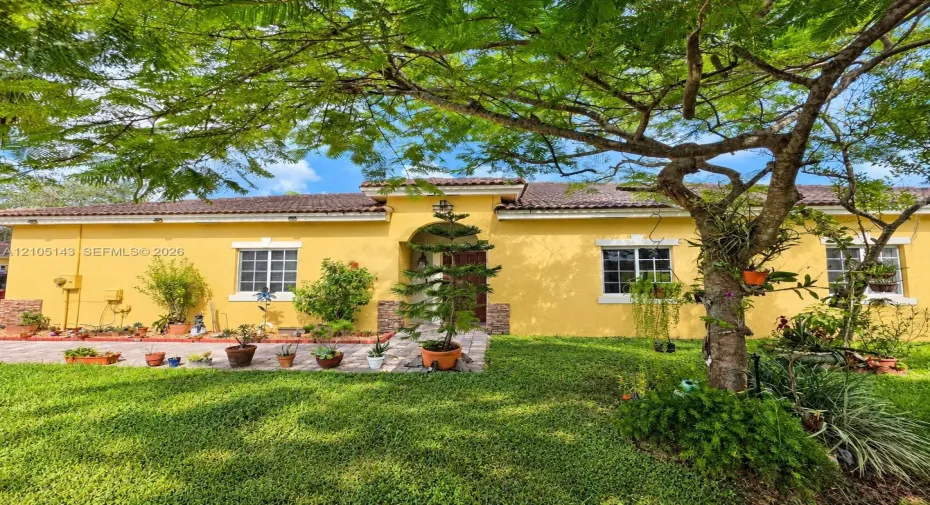Yellow exterior with a tiled roof, decorative stone accents, and multiple windows with white frames