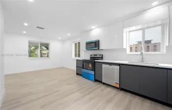 White cabinetry, stainless steel appliances, light wood-finish flooring, recessed lighting, and a kitchen sink with a gooseneck faucet