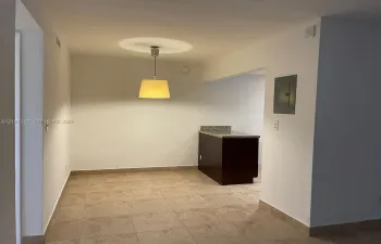 Tiled flooring, recessed ceiling light, pendant light fixture, built-in cabinetry with stone-finish countertop