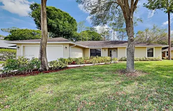 Single-story exterior with a cream stucco finish, two-car garage with white doors, white front entry door, and a shingled roof
