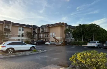 Multi-story building featuring stucco exterior, metal mansard roofline, private balcony access, and dedicated surface parking