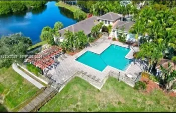 Expansive outdoor pool with paver decking, adjacent pergola, waterside location, and wood-finish boardwalk