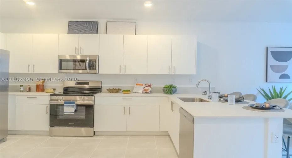 Kitchen featuring flat-panel white cabinetry, stainless steel appliances, solid-surface countertops, recessed lighting, and tile flooring