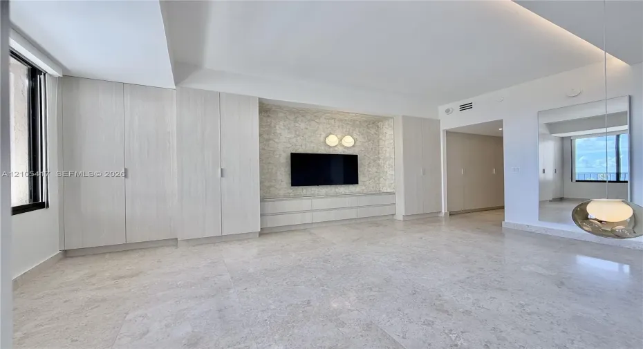 Light-toned tile flooring, built-in light wood-finish cabinetry, and a recessed entertainment area with accent lighting