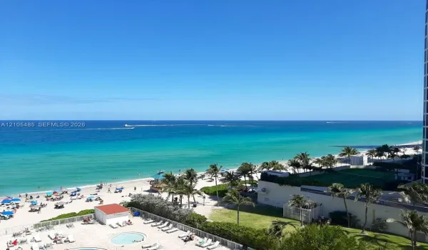 Expansive oceanfront setting featuring a sandy beach, clear blue water, and palm trees
