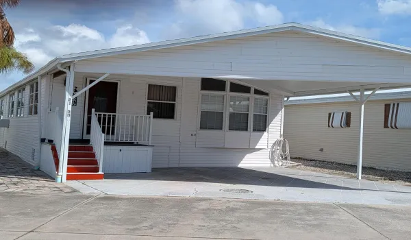 White siding exterior with an attached carport, covered entry, and red-painted steps
