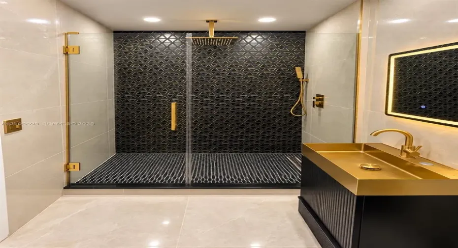 Walk-in shower with geometric mosaic tile and gold-finish fixtures
