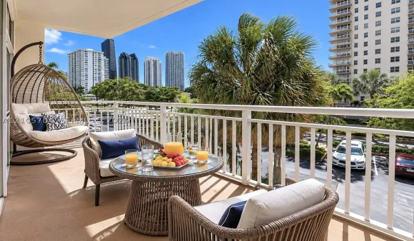 Private covered balcony featuring white metal railings and concrete flooring