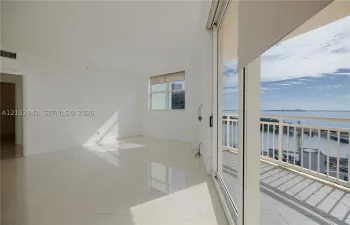 Interior space featuring polished tile flooring, full-height sliding glass doors, and a private balcony with metal railing