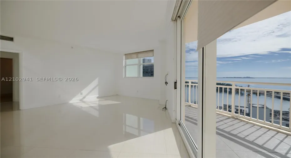 Interior space featuring polished tile flooring, full-height sliding glass doors, and a private balcony with metal railing