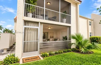 Two-story exterior featuring double-stacked screened-in patios, stucco facade, metal lower-level screening, and flush-mount ceiling lighting