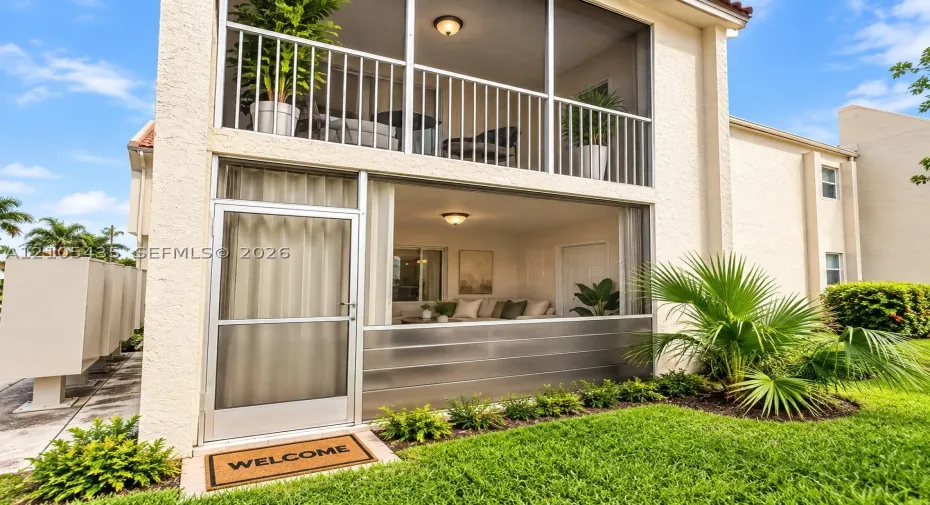Two-story exterior featuring double-stacked screened-in patios, stucco facade, metal lower-level screening, and flush-mount ceiling lighting