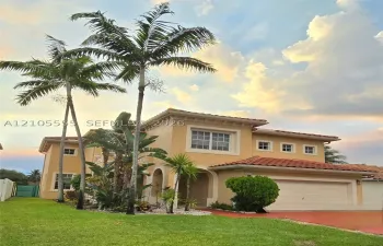 Two-story stucco exterior featuring a clay tile roof, arched entryway, and multi-paned windows
