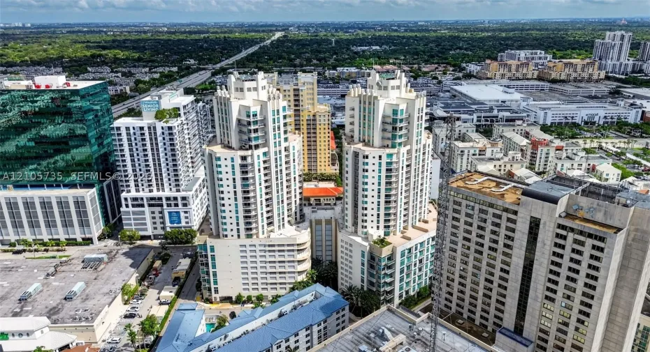 Aerial perspective of dual-tower high-rise residential architecture featuring glass-paneled balconies and a central podium structure