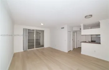 Wood-finish flooring, sliding glass door to a balcony with metal railings, built-in breakfast bar, white cabinetry, and recessed lighting