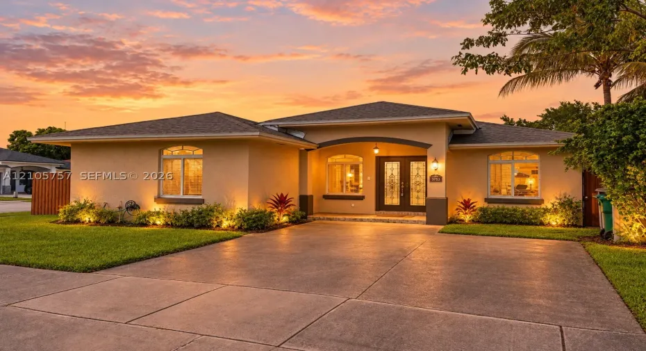 Stucco exterior featuring an arched entryway, double front doors with decorative glass inserts, and a concrete driveway