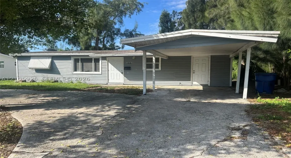 Single-story residence featuring light gray horizontal siding, a covered carport, and a concrete driveway