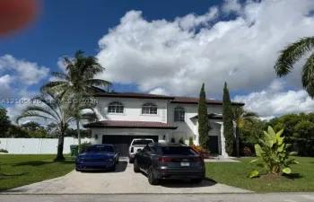 Two-story residence with a tile roof, stucco exterior, arched window detailing, and a concrete driveway leading to a multi-car​​‌​​​​‌​​‌‌​‌‌​​​‌‌​‌​‌​‌​​​‌​​ garage