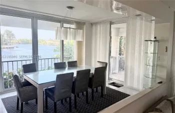 Floor-to-ceiling glass windows, recessed ceiling lighting, built-in display cabinetry, and polished flooring featuring direct water access to a balcony