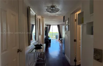 Interior hallway featuring wood-finish flooring, a contemporary semi-flush mount ceiling fixture, and sliding glass doors with access to an exterior balcony