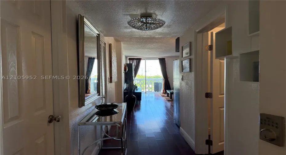 Interior hallway featuring wood-finish flooring, a contemporary semi-flush mount ceiling fixture, and sliding glass doors with access to an exterior balcony