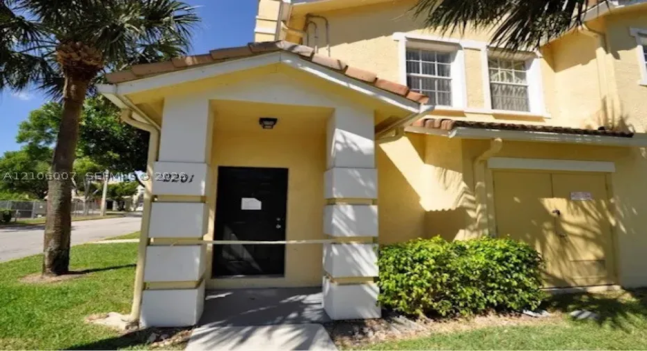 Stucco exterior featuring a covered entryway with structural columns, tile roof accents, and multi-pane windows