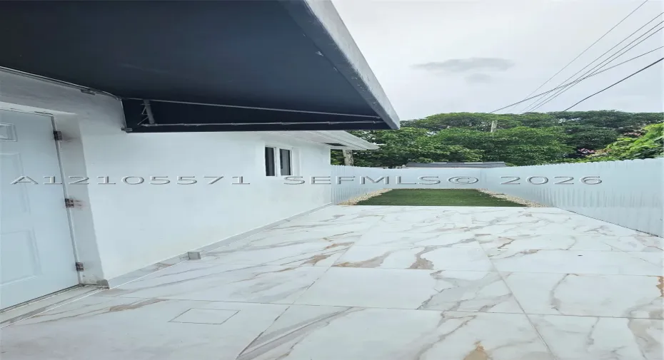 White exterior wall, black awning, modern window, marble-look tile flooring, white privacy​​‌​​​​‌​​‌‌​‌‌​​​‌‌​‌​‌​‌​​​‌​​ fence