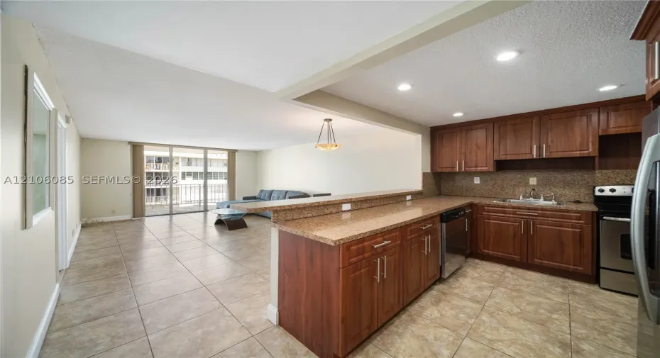 Kitchen featuring wood cabinetry, stone-finish countertops, tile flooring, recessed lighting, and a breakfast bar