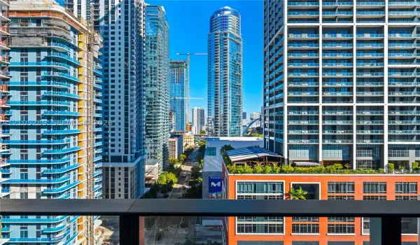 Cityscape featuring multiple high-rise structures, balconies with glass railings, and a prominent building with a blue glass exterior