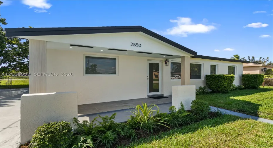 Single-story exterior featuring a textured stucco facade, covered porch with recessed lighting, and architectural gable roofline