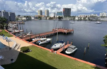 Waterfront property featuring a wood-plank boat dock with slips, stone-paver patio, and grass lawn