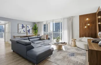Open-concept living space featuring wood-finish flooring, floor-to-ceiling glass sliding doors, and a wood-paneled accent wall with integrated multi-globe lighting