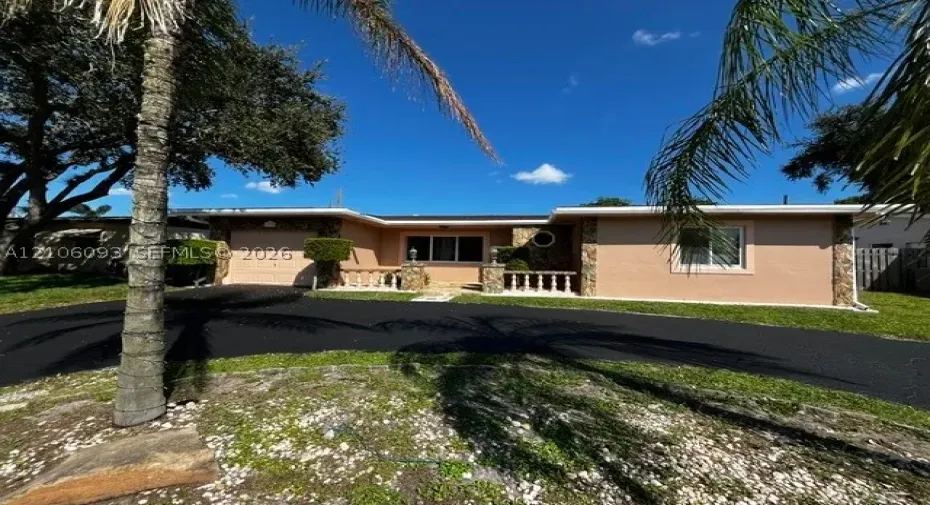 Single-story exterior featuring stucco siding, stone veneer accents, an asphalt driveway, and a decorative concrete balustrade
