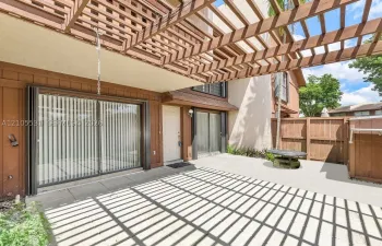 Private patio featuring a wooden pergola, concrete surfacing, and wood fencing